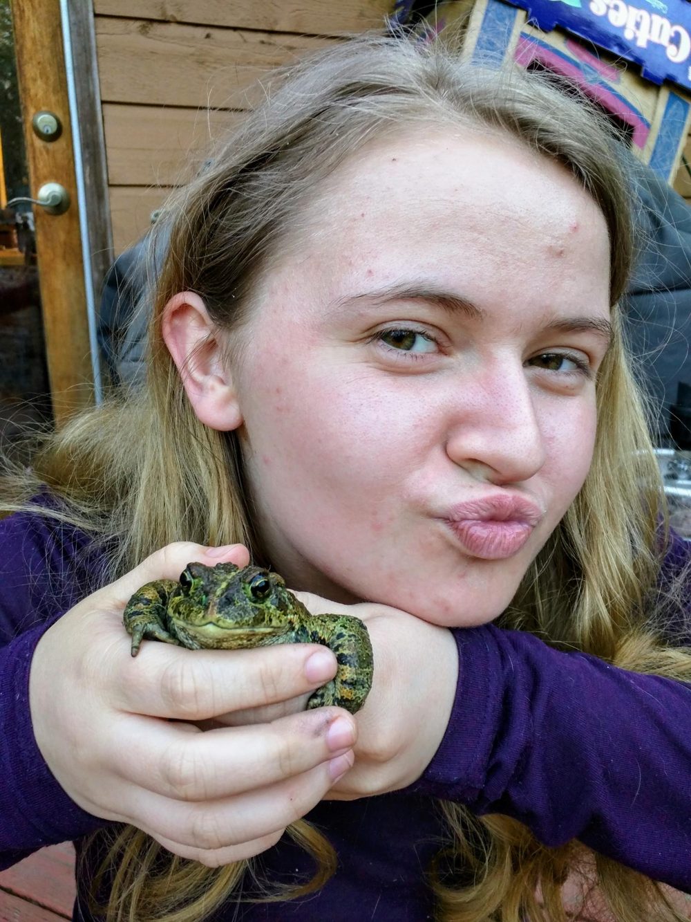Marly holding a toad and making a kissy face at the camera